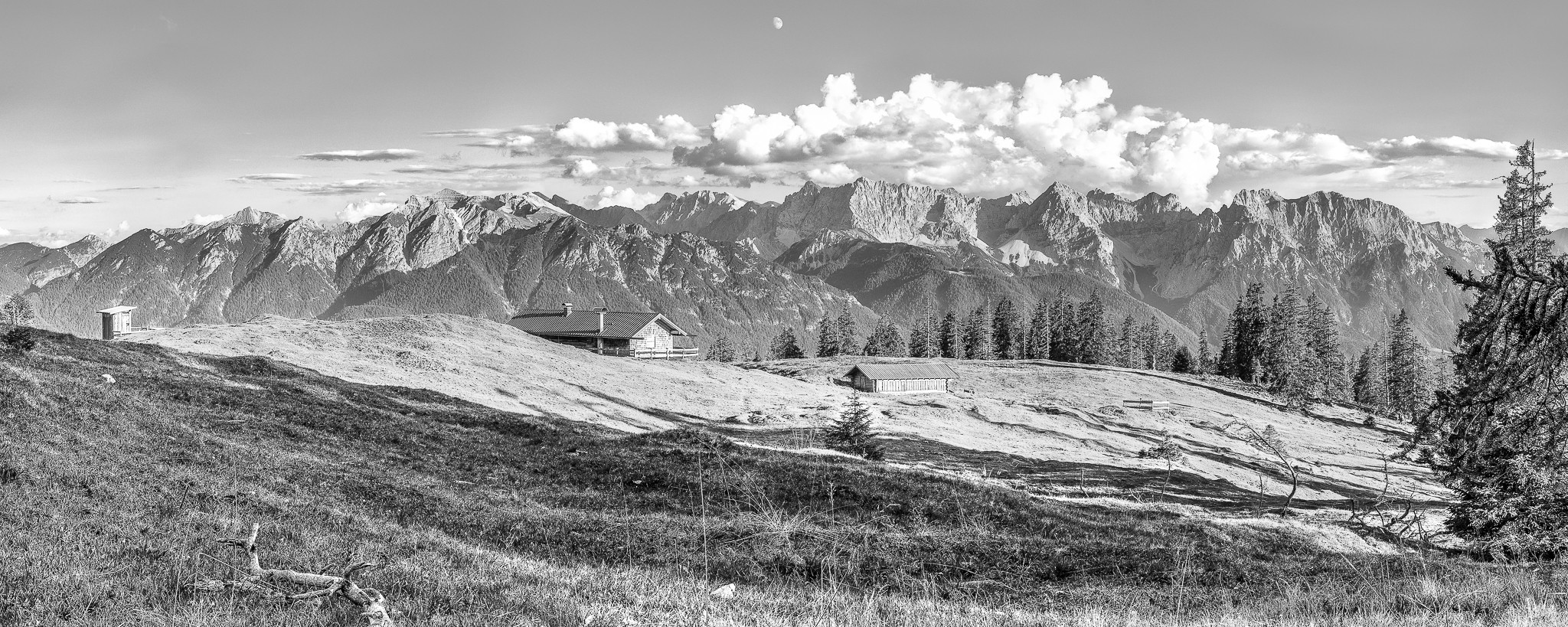 Die Krüner Alm mit Plumsklo und Kuhstall! Urig! Fantastischer Panorama Ausblick von der Krüner Alm auf die Soierngruppe und das Karwendelgebirge. Die Schatten der Bäume auf der Almwiese geben dem Schwarz-Weiß-Bild einen interessanten Kontrast.