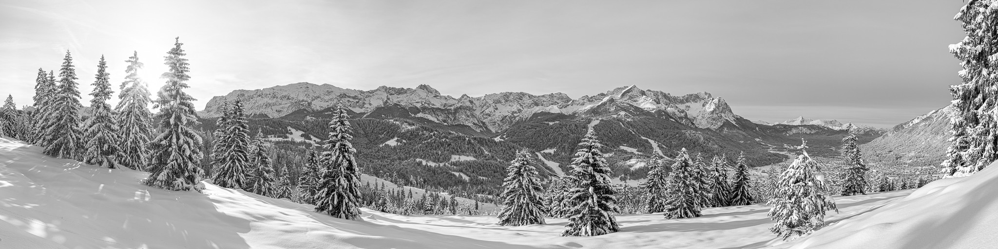 Schwarz-weiß: Winterwald oberhalb von Garmisch-Partenkirchen mit einem wunderbaren Panoramablick auf das Wettersteingebirge mit Zugspitze und Alpspitze.