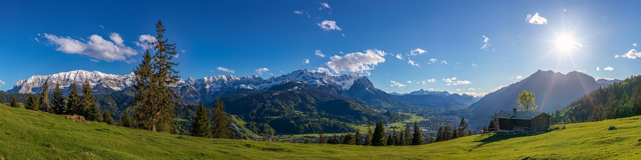 Bergpanorama mit Almhütte über Garmisch-Partenkirchen. Blick auf das Wettersteingebirge mit Alpspitze und Zugspitze und auf der rechten Seite der Kramer.