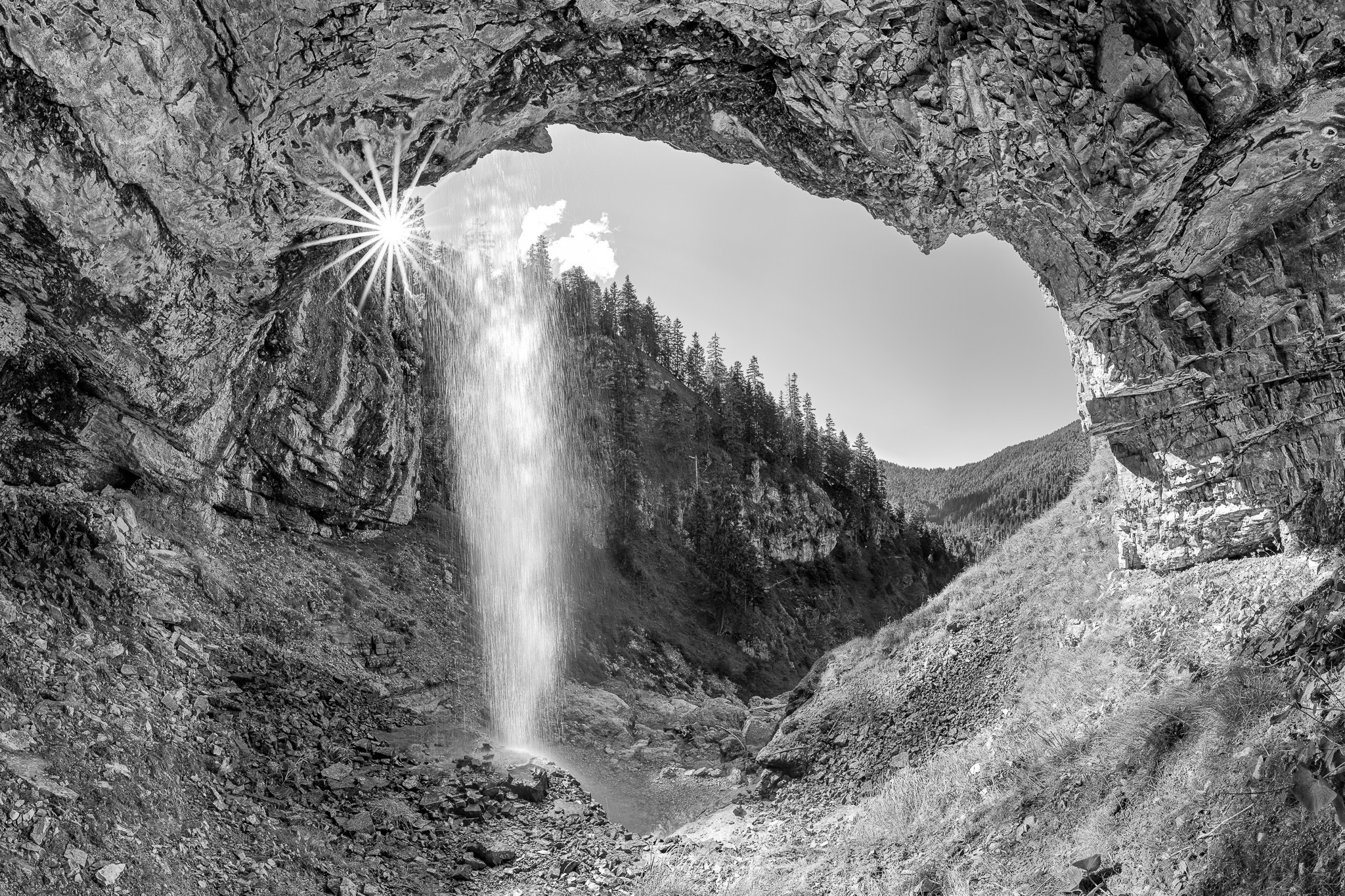 Wasserfall-Ausblick. Ausblick aus einer Höhle unter einem hohen Wasserfall im Karwendelgebirge. s-w