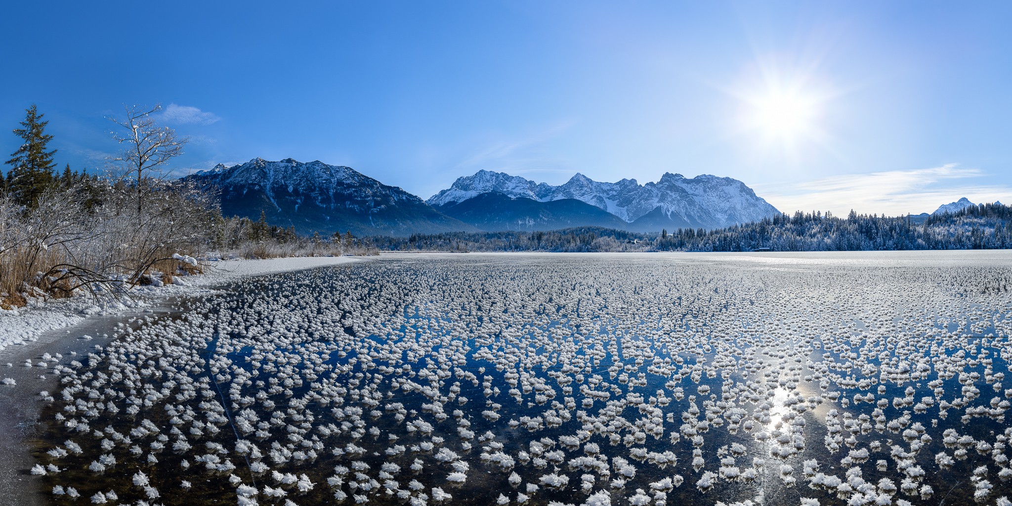 Eisrosen am Barmsee. Winterlandschaft am zugefrorenem See mit vielen Eisrosen / Eiskristallen. Blick auf die Soierngruppe und das Karwendelgebirge.
