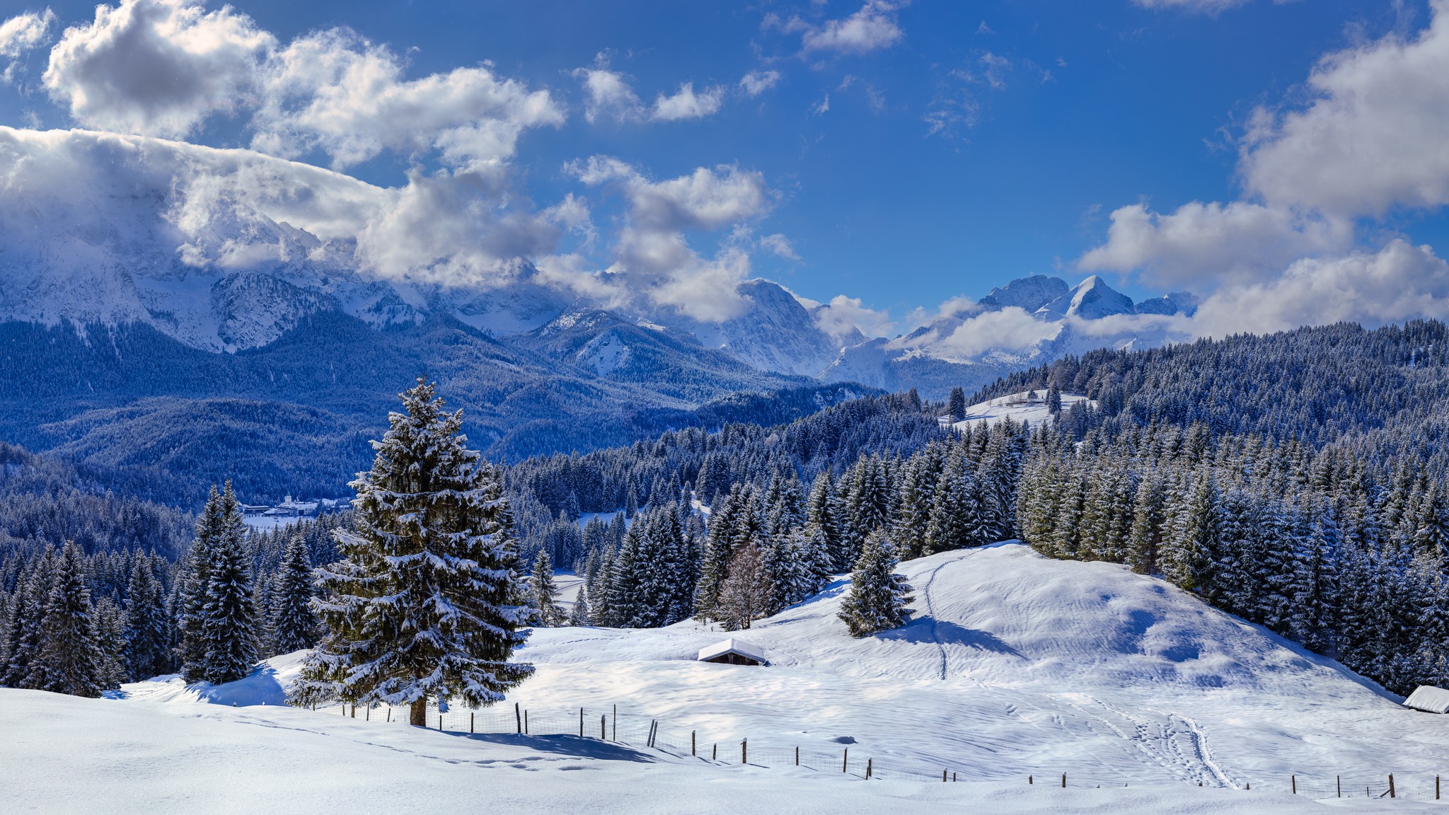 Wintertag in Elmau - Traumwetter, die Wolken ziehen umher und geben immer wieder den Blick auf die Alpspitze und die Zugspitze frei. Links unten ist das Schloss Elmau und etwas weiter rechts oben die Elmauer Alm.
