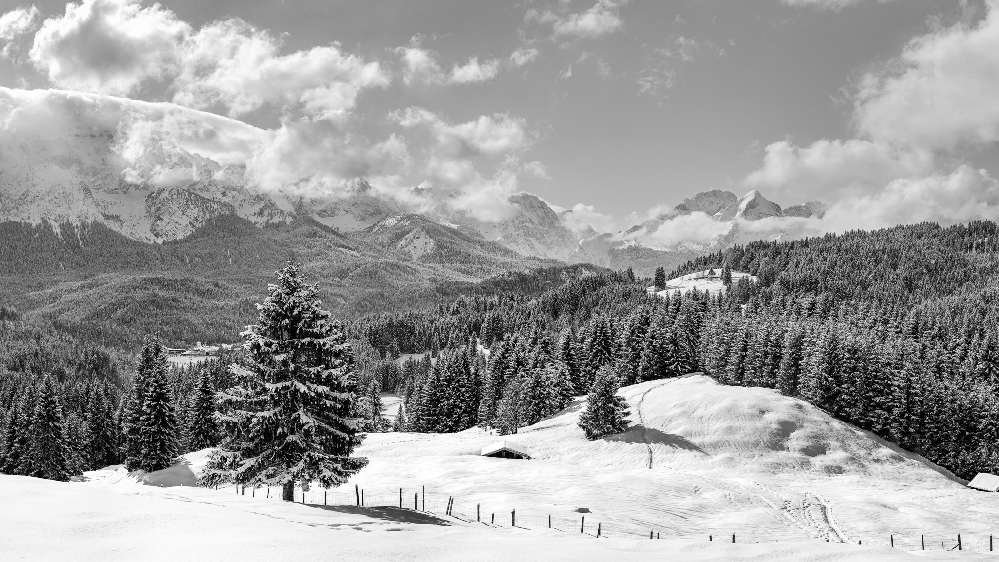 Schwarz weiß - Wintertag in Elmau - Traumwetter, die Wolken ziehen umher und geben immer wieder den Blick auf die Alpspitze und die Zugspitze frei. Links unten ist das Schloss Elmau und etwas weiter rechts oben die Elmauer Alm.